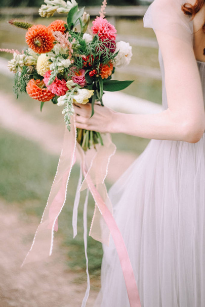bride in a dress with open hands holding a bouquet of flowers - Fotoğraf, Görsel