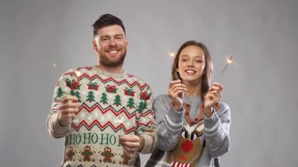 celebration, fun and holidays concept - happy couple wearing knitted sweaters with sparklers dancing at christmas party - Video