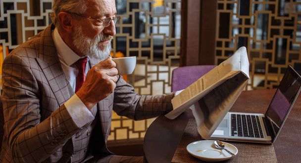Starý podnikatel s notebookem při přestávce na kávu v jeho kancelářské koncepci - Fotografie, Obrázek