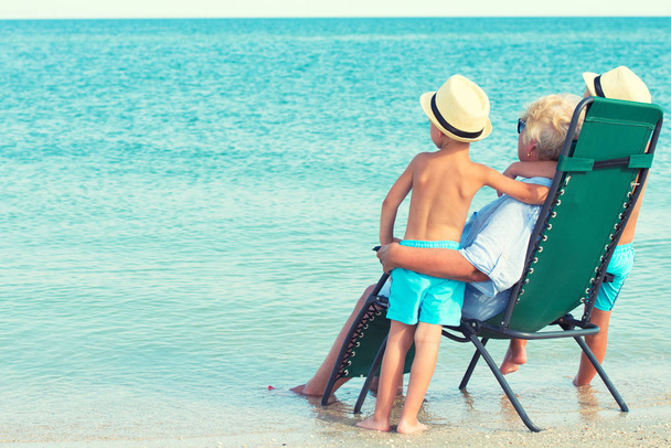 Grandchildren with their grandmother are resting and looking at the sea. Summer vacations. - Photo, Image