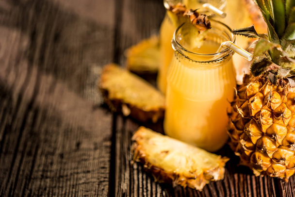 Pineapple juice and slice placed on a wooden table - Foto, imagen
