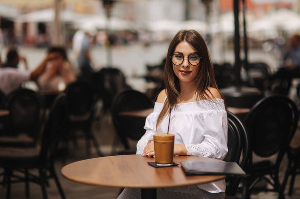 Élégante jeune femme heureuse portant une chemise blanche. Elle tient du café. portrait de fille souriante dans des lunettes de soleil
 - Photo, image