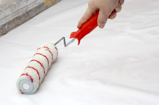 жінка робить ремонт, змащує шпалери клеєм на підлогу
 - Фото, зображення