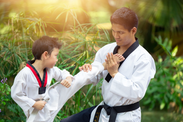 Niño y papá disfrutar de un deporte saludable Taekwondo juntos al aire libre para el tren de patada de combate
. - Foto, imagen