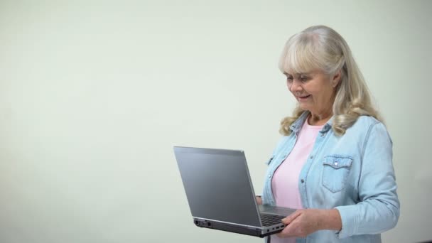 Elderly lady surprised with message on laptop, modern technologies for retirees - Materiał filmowy, wideo