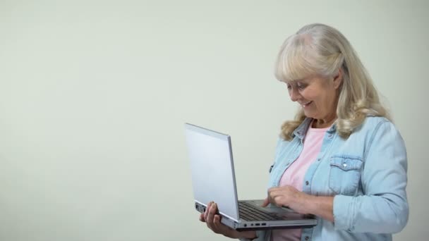 Aged lady typing on laptop showing thumbs-up, computer literacy for retirees - Filmagem, Vídeo