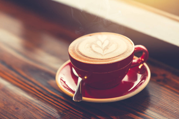 Dobry poranną kawę w windows na drewnianym stole tonem vintage kolor latte art. - Zdjęcie, obraz