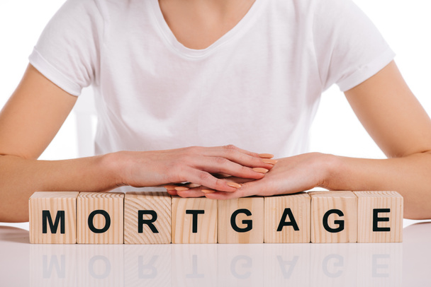 cropped view of woman with hands on wooden cubes with mortgage lettering isolated on white - 写真・画像