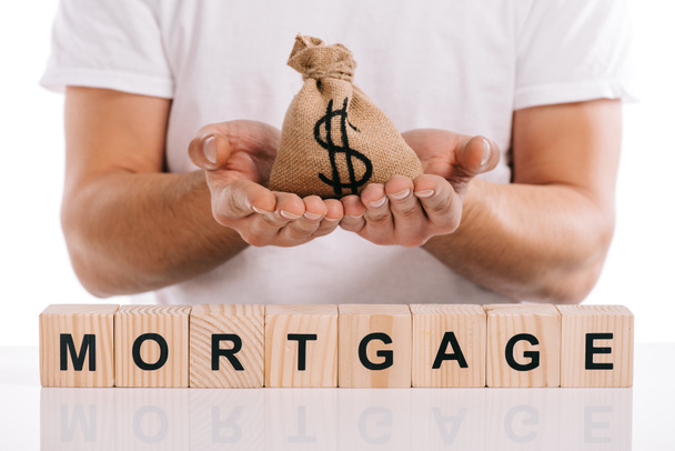 cropped view of man holding moneybag near cubes with mortgage lettering isolated on white - Foto, Imagen