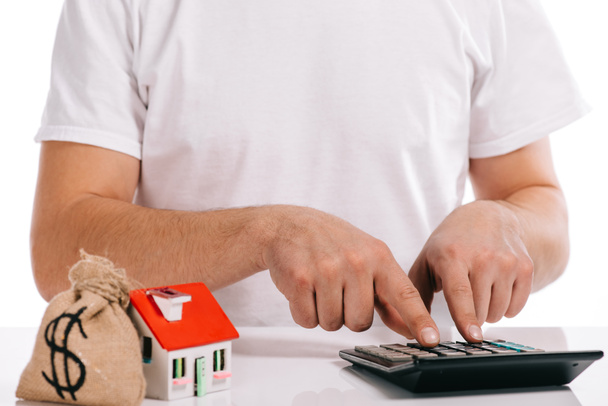 cropped view of man calculating near moneybag and house model isolated on white, mortgage concept - Photo, Image