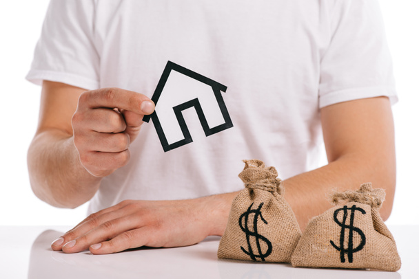 cropped view of man holding paper house near moneybags isolated on white, mortgage concept - Photo, Image