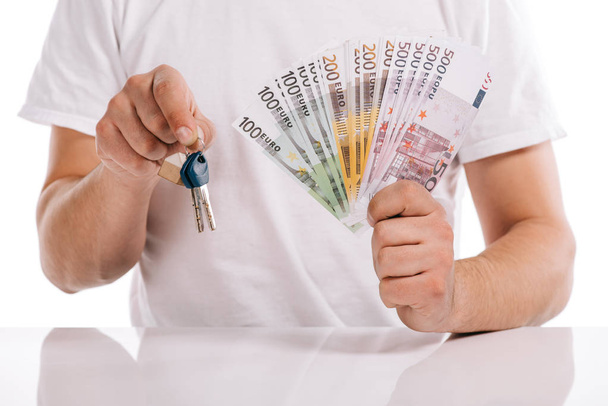 concept bijgesneden weergave van man met contant geld en sleutels op wit wordt geïsoleerd, hypotheek - Foto, afbeelding