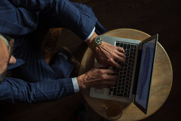 Senior dramatist looking at laptop, creating novel while sitting in pub. - Photo, image