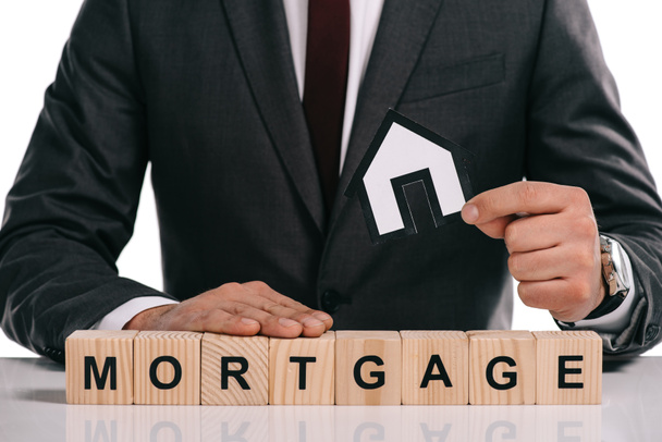 cropped view of mortgage broker holding paper house near wooden blocks isolated on white - Photo, Image