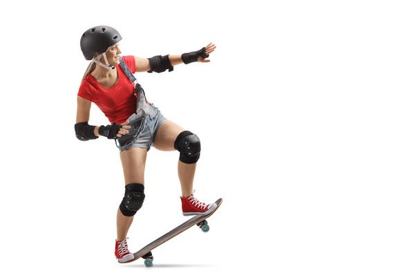 Full length shot of a skater girl with a skateboard and helmet isolated on white background - 写真・画像
