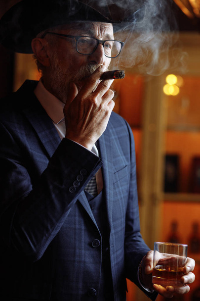 Portrait of old-aged male dandy in big hat smokes cigar and drin - Fotoğraf, Görsel