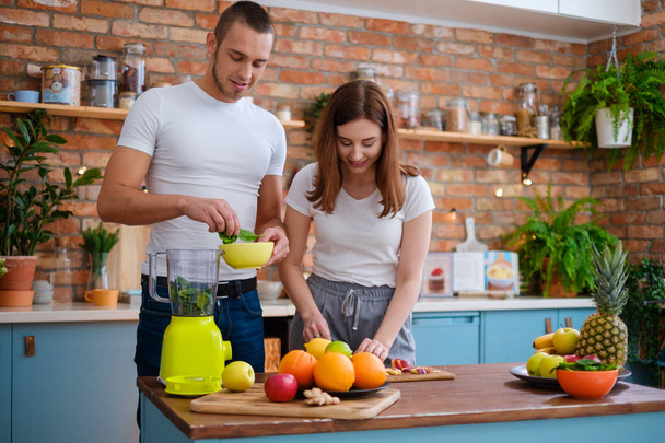Νεαρό ζευγάρι κάνει smoothie στην κουζίνα - Φωτογραφία, εικόνα
