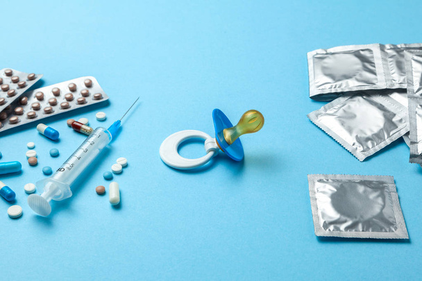 Birth control pills, een injectiespuit en condoom in een pakket op blauw. methode van anticonceptie, pil of condoom - Foto, afbeelding