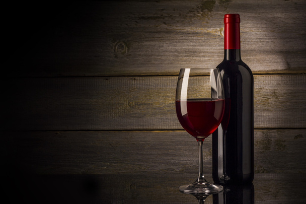 Ποτήρι κρασιού και μπουκάλι σε ξύλινο φόντο - Φωτογραφία, εικόνα