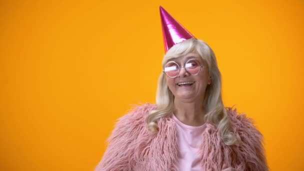 Happy aged woman in pink coat and round glasses celebrating birthday anniversary - Кадры, видео