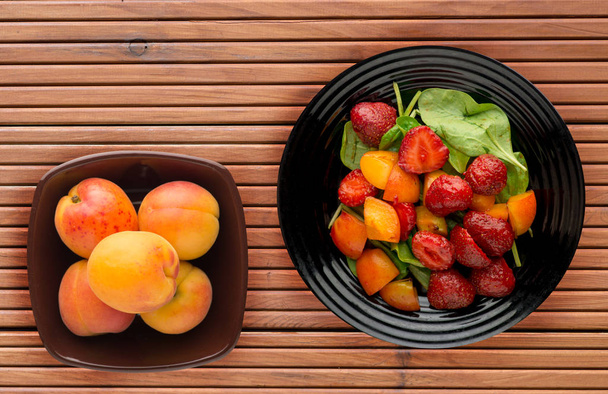 vegetarian food . healthy food. a salad of spinach, apricot, strawberry on a plate on a wooden background. - Fotoğraf, Görsel