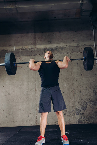 sporty guy working out with barbell at gym - Zdjęcie, obraz
