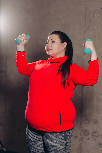 fat woman exercising with dumbbells in the studio - Foto, Imagem