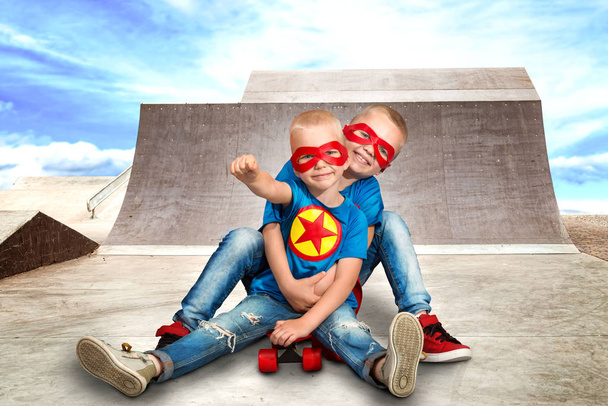 Children in superhero costumes riding on steep hills to skateboard at the skate Park.Extreme sports. - Foto, afbeelding