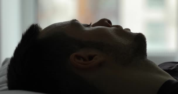 Closeup of male face and eye wake up in bed at the morning - Materiał filmowy, wideo