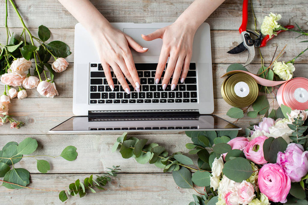 Szczelnie-do góry ręce, klawiatury laptopa i kwiatowy tabeli. Kobieta blogger i treści twórców sieci społecznych i kwiaciarnię blogu. Koncepcja sklepu internetowego i dostawy kwiatów. SMM promocja - Zdjęcie, obraz
