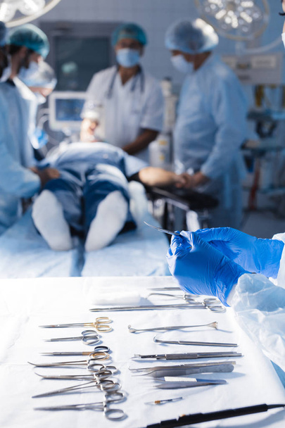 Surgical tools lying on table with nurse near and surgeons at background. - Photo, Image