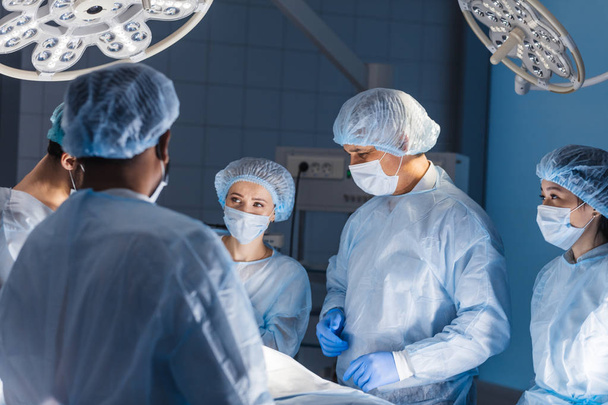 Διαφορετική ομάδα χειρουργών, βοηθών και νοσηλευτών που κάνουν επεμβατική χειρουργική - Φωτογραφία, εικόνα