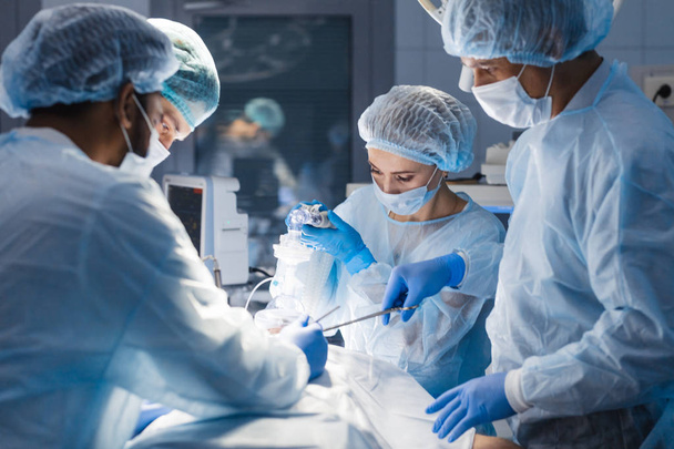 Diverse Team of surgeon, assistants and nurses making invasive surgery - Fotó, kép