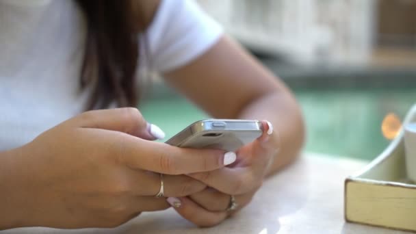 Ręce dziewczyny z biały manicure wiadomości tekstowe na telefon komórkowy w kafeterii zbliżenie Oszałamiająca kobieta ręce seksowny z białym manicure przeglądania sieci i SMS-y szybko na jej musujące smartphone w przestronnej stołówce. - Materiał filmowy, wideo