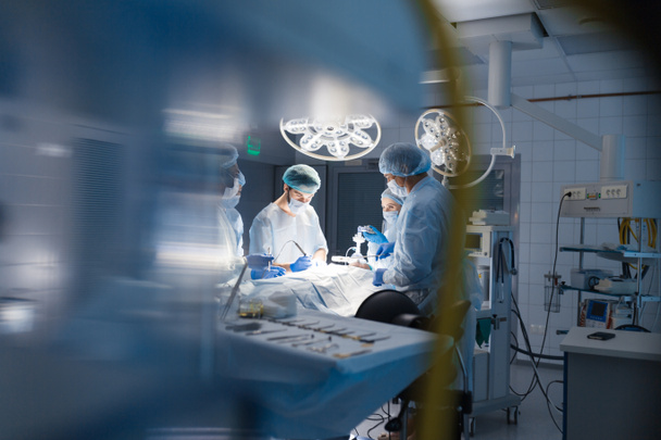 Розмитий фон з командним хірургом на роботі в операційній
 - Фото, зображення