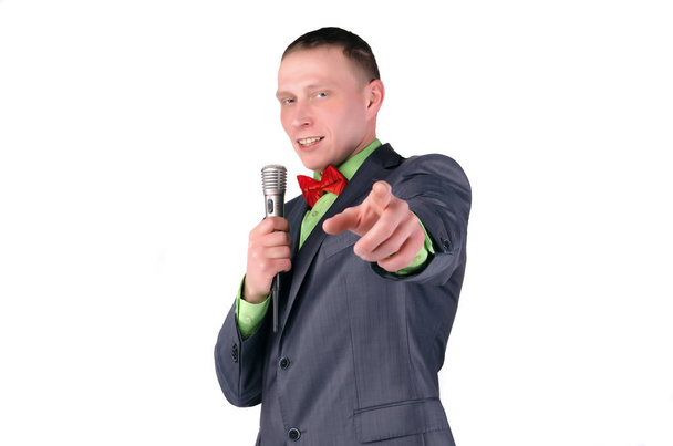 Happy presenter or businessman with microphone in the hands is showing ahead by his index finger isolated on white background. - Fotoğraf, Görsel