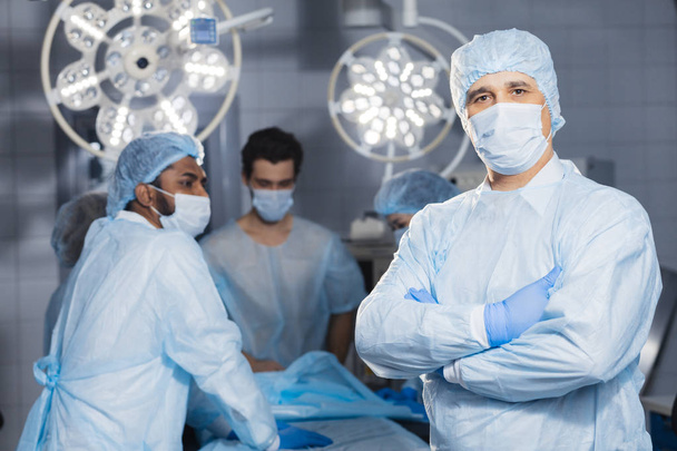 Senior doctor, surgeon wearing medical protective mask in operating room - Фото, зображення