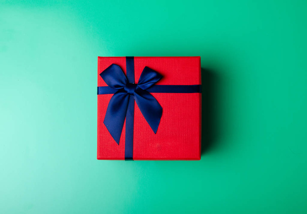 Red box gift with blue ribbon on green background - Φωτογραφία, εικόνα