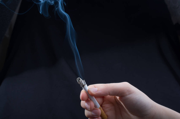 Hand hält rauchende Zigarette mit Rauch herum - Foto, Bild