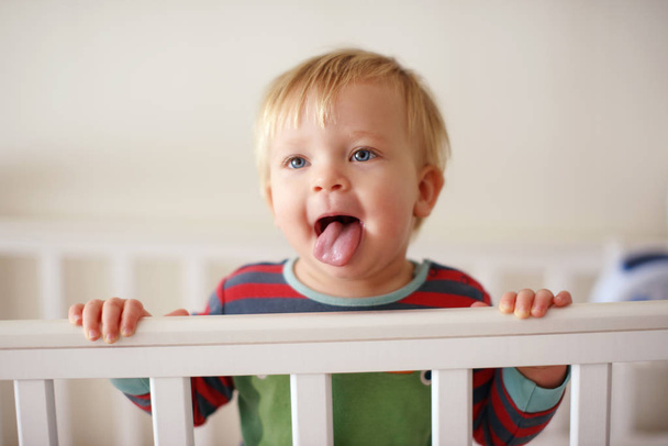 funny baby standing in the bed and showing tongue - Foto, Imagem