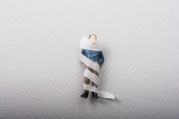 Winzige Figur des Mannes Miniaturmodell in Bandagen gewickelt - Foto, Bild