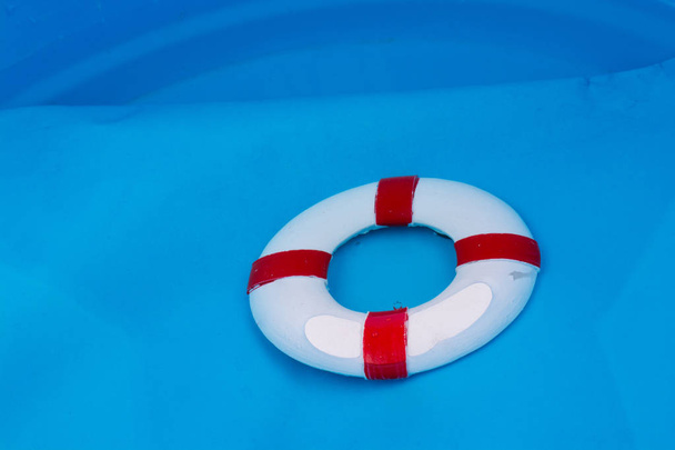 Little red and white color model life buoy in water - Foto, afbeelding