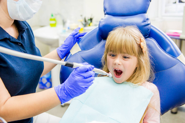 Kleine meisje sitts in het kantoor van tandartsen - Foto, afbeelding
