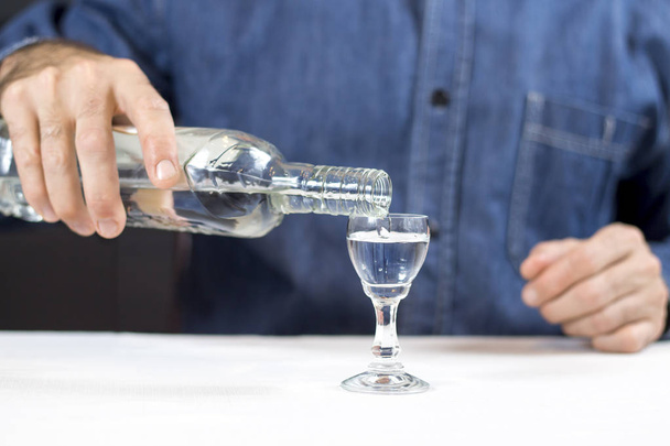 male hand pours vodka from the bottle into the glass. - Valokuva, kuva
