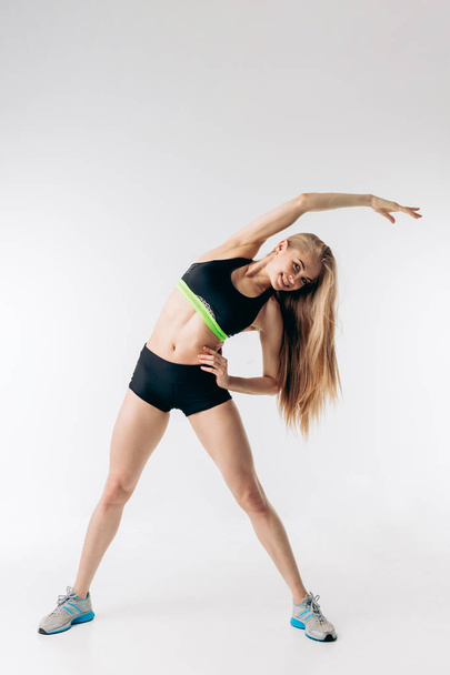 Young positive woman doing side bend - Foto, imagen