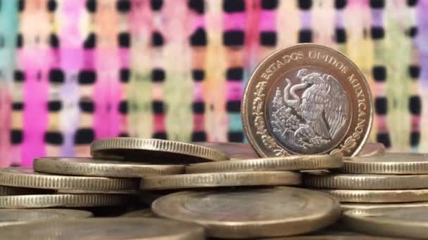 Mexikanische Münze rotiert über andere mexikanische Münzen mit buntem Hintergrund - Filmmaterial, Video
