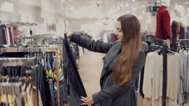 junge schöne Frau findet sich neue Kleider in einem Supermarkt - Filmmaterial, Video