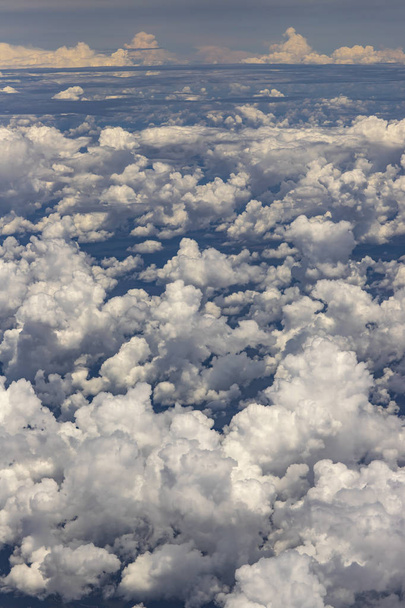 Прекрасний вид з вікна літака, що літає над хмарами. Природна панорама з хмарами. Білі хмари рухаються над землею
.  - Фото, зображення