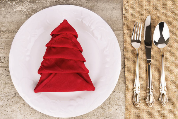 Close up on Christmas table settings with a decorative napkin on a plate, directly above. - Foto, Imagen