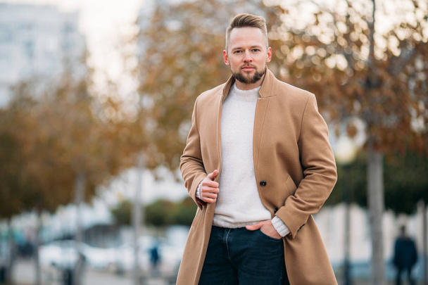 Portrait of confident man in brown coat and white sweater. - Foto, afbeelding
